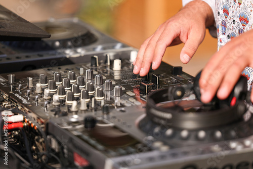 Photo with the hands of a DJ mixing outdoor in a garden party. Electronic music deejay concept photo.