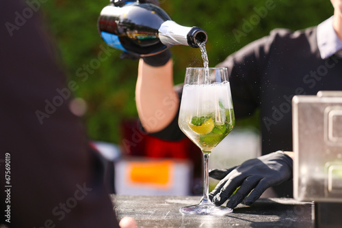 Hugo cocktail alcoholic aperitif. Photo while a bartender prepares Hugo cocktails drinks with prosseco lime ice, elderflower syrup and mint. Dark background.