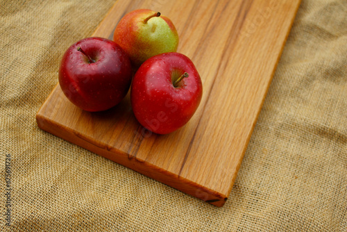 Fruits on a wooden cutting board - two apples and a pear