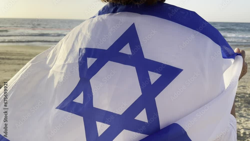 Woman in white clothes hold Israeli flag in two hands above head. background seaside and sunset. freedom and nationality.