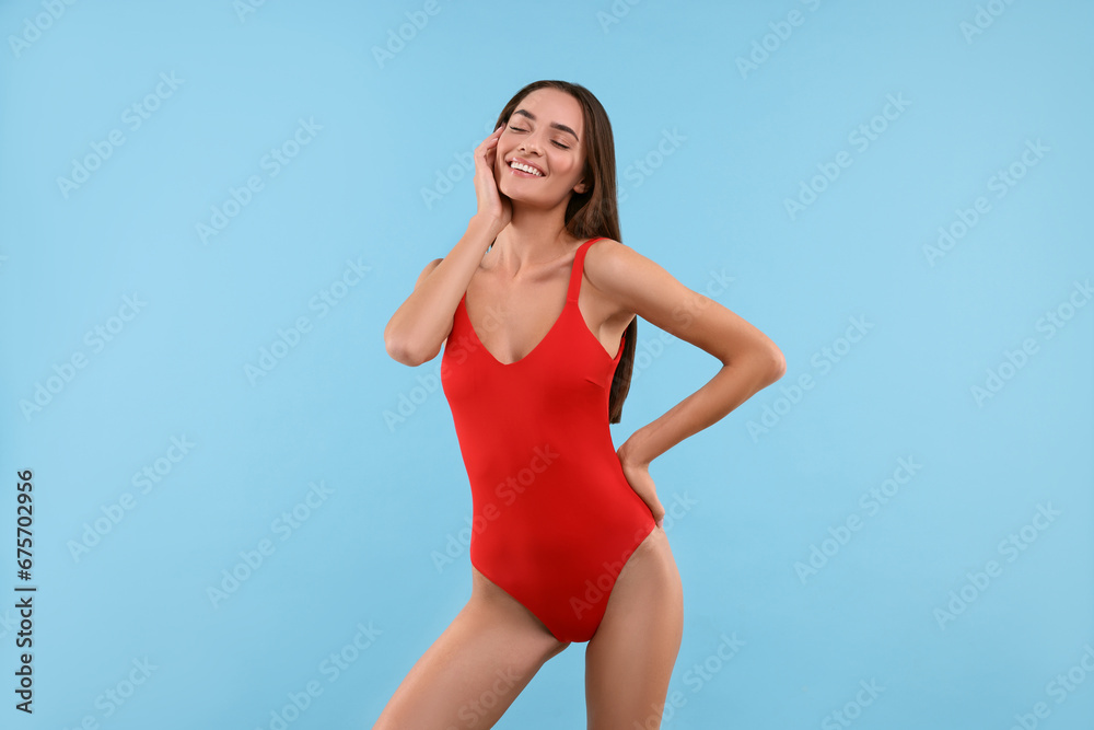 Young woman in stylish swimsuit on light blue background Young woman in stylish swimsuit on light blue background