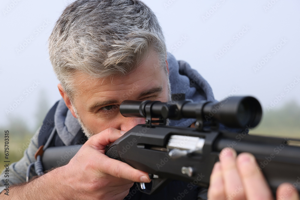 Man aiming with hunting rifle outdoors, closeup Man aiming with hunting rifle outdoors, closeup