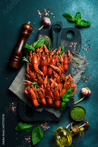 Hot spicy boiled crayfish and spices on a wooden board. On dark rustic background. Seafood and lobsters.
