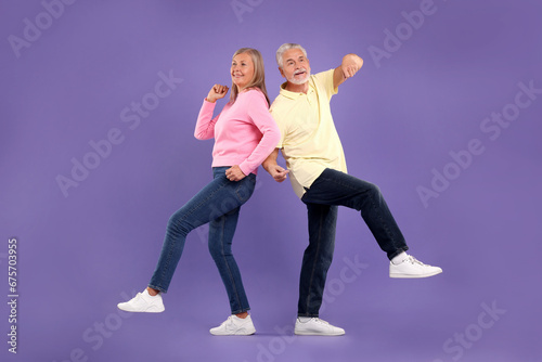 Senior couple dancing together on purple background