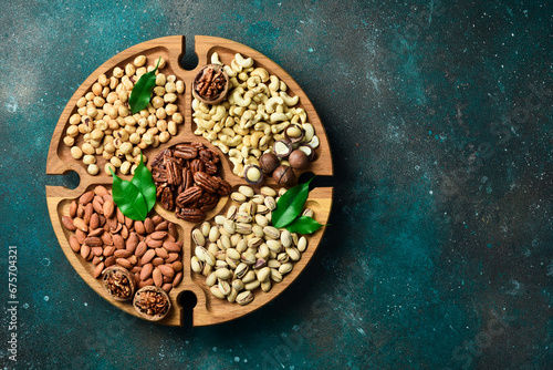 Assortment of nuts on a wooden plate. Top view. Mixed nuts on wooden table. On a dark background.