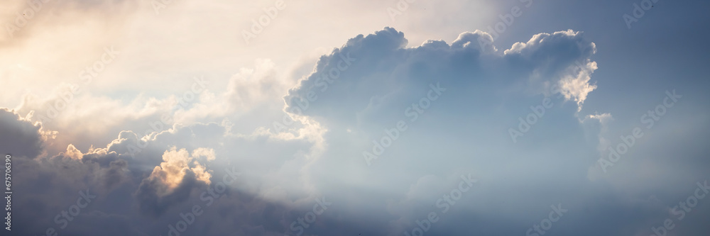 Beautiful sky background with clouds and sunbeams. Dramatic cloudscape with sun rays. Wide panoramic background for design.