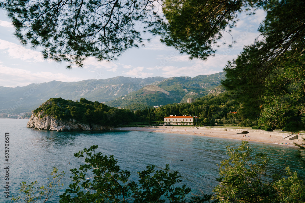 View through the branches of trees on the royal beach near Villa Milocer at the foot of the mountains. Montenegro