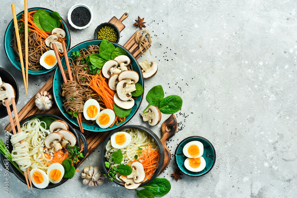 A set of Asian dishes with noodles. Udon and soba noodles. On a concrete gray background. Top view.