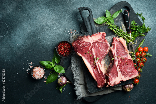 Two Raw T-bone Steak with fresh herbs and ready to cook. A piece of veal. photo