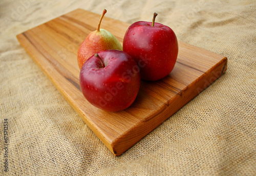 Fruits on a wooden cutting board - two apples and a pear