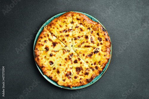 Georgian khachapuri with cheese. Pizza with cheese. On a black stone background. In a plate, close-up.