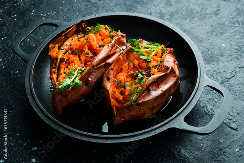 baked sweet potato with garlic, herbs and spices. On a stone background. Side view.