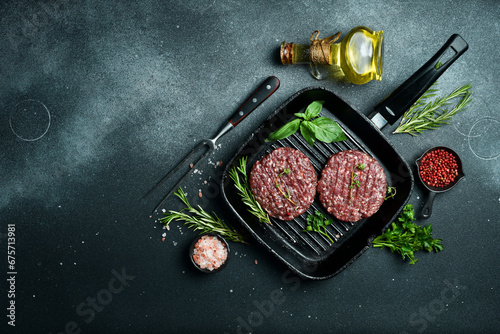 round burger patty with spices and herbs on a pan. Cooking a burger. On a dark stone background. Top view.