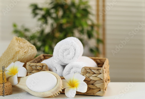 Composition with different spa products and plumeria flowers on white table indoors, closeup
