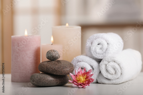 Spa composition. Burning candles, lotus flower, stones and towels on white table