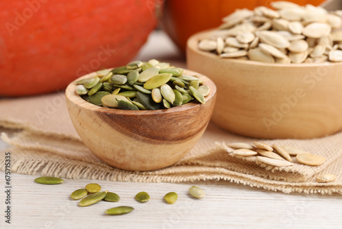 Bowls with pumpkin seeds on light wooden table