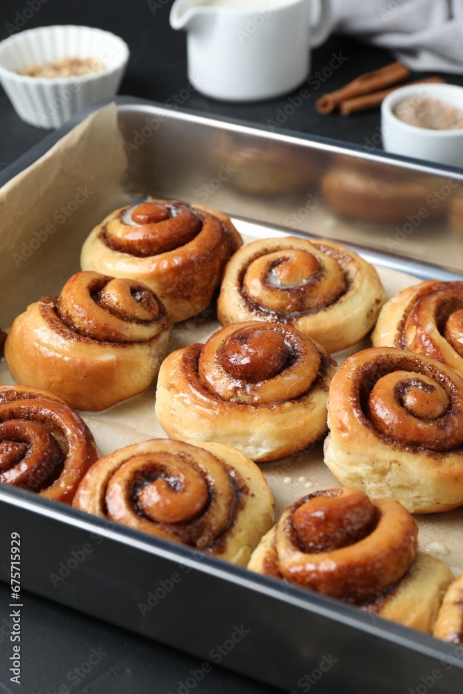 Baking dish with tasty cinnamon rolls on dark table Baking dish with tasty cinnamon rolls on dark table