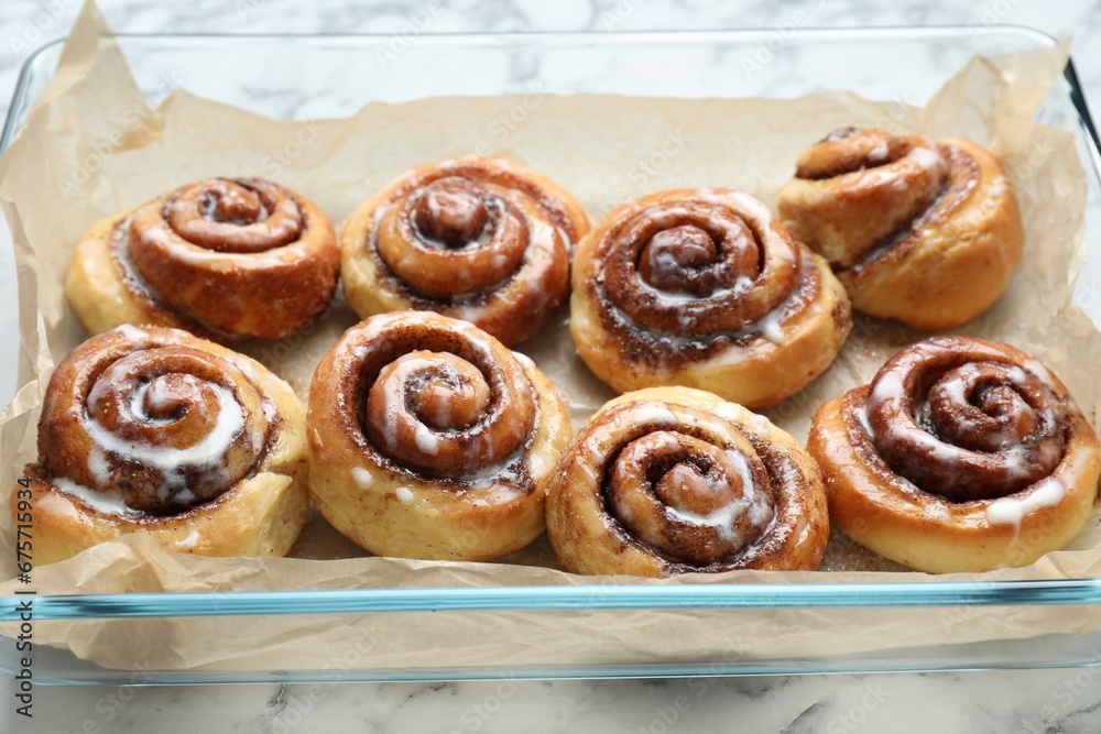 Baking dish with tasty cinnamon rolls on white marble table, closeup Baking dish with tasty cinnamon rolls on white marble table, closeup