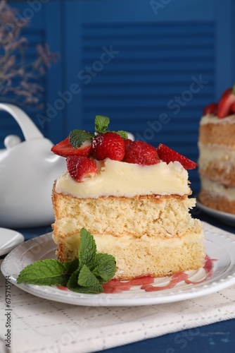 Piece of tasty cake with fresh strawberries and mint on blue wooden table, closeup