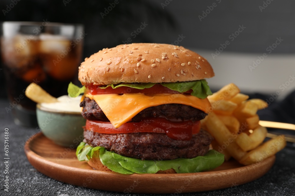 Tasty cheeseburger with patties, sauce and French fries on grey textured table, closeup