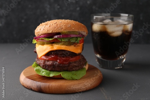 Tasty cheeseburger with patties and soda drink on grey table