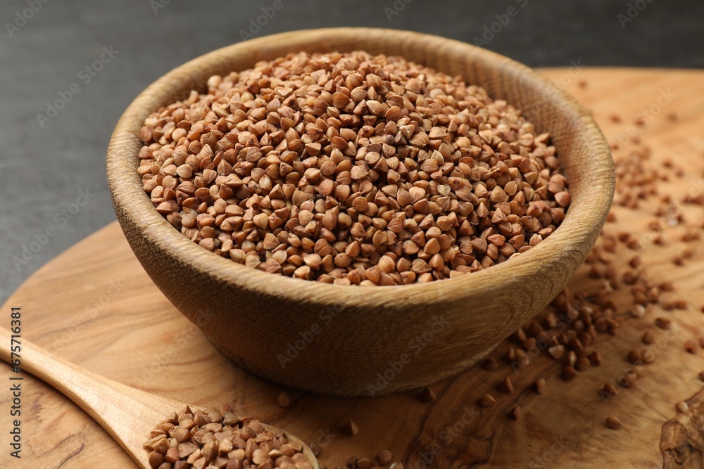 Bowl and spoon with dry buckwheat on table, closeup Bowl and spoon with dry buckwheat on table, closeup