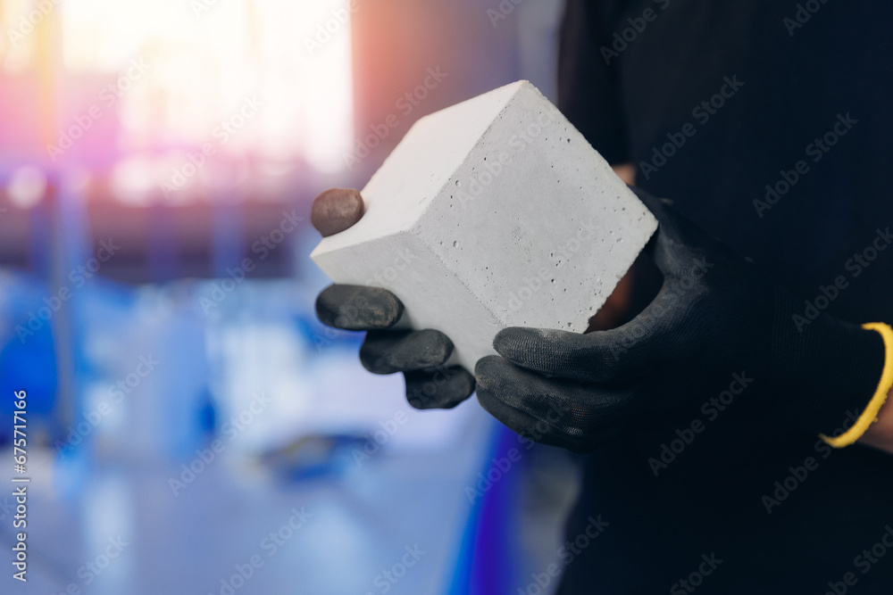 Engineer hold concrete cube in industry lab for testing building materials. Controls size and quality of cement mortar