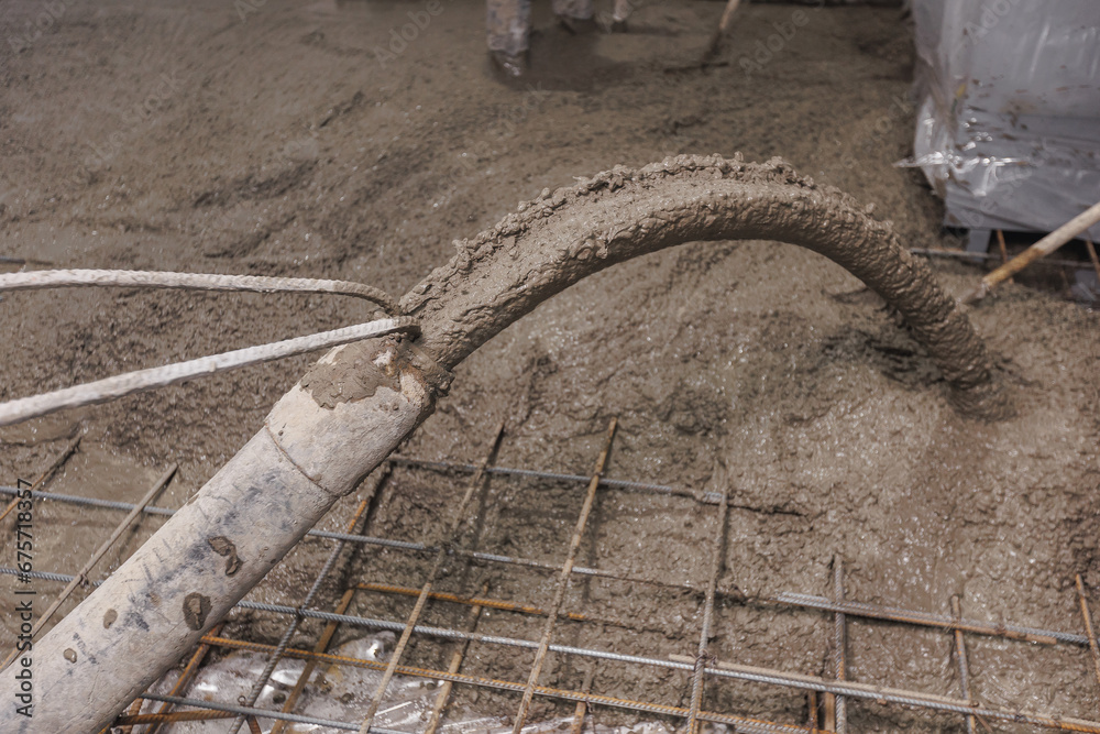 Building site, workers with pipe move concrete to reinforced structures