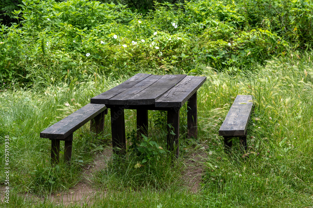 Two wooden benches and a large dining table in the forest. A place to rest in nature. Two wooden benches and a large dining table in the forest. A place to rest in nature.