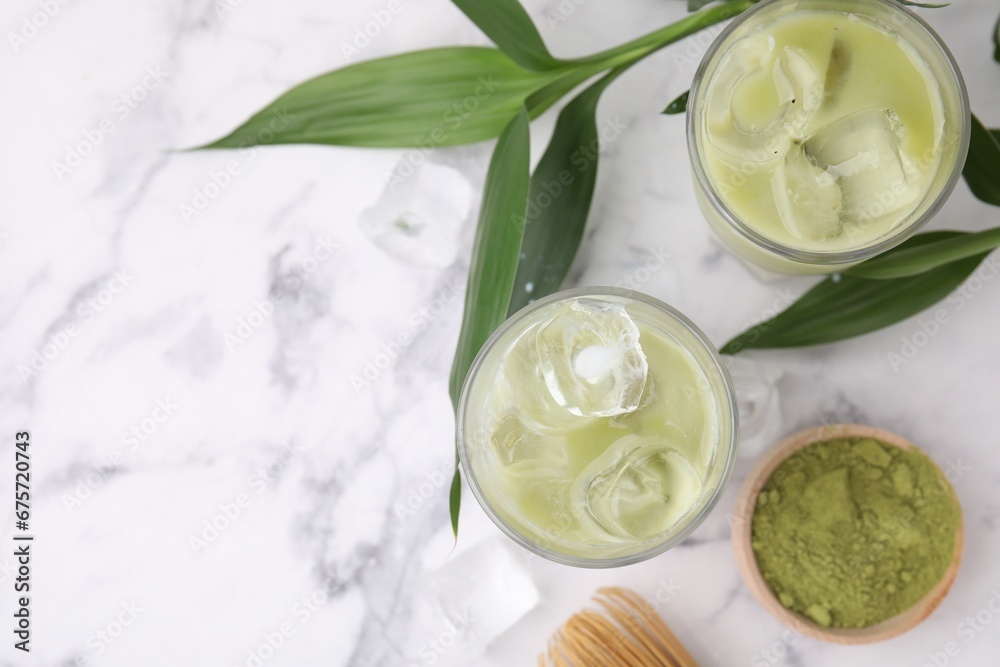 Glasses of tasty iced matcha latte, powder and leaves on white marble table, flat lay. Space for text Glasses of tasty iced matcha latte, powder and leaves on white marble table, flat lay. Space for text