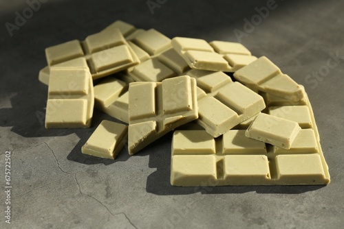 Pieces of tasty matcha chocolate bars on grey textured table  closeup