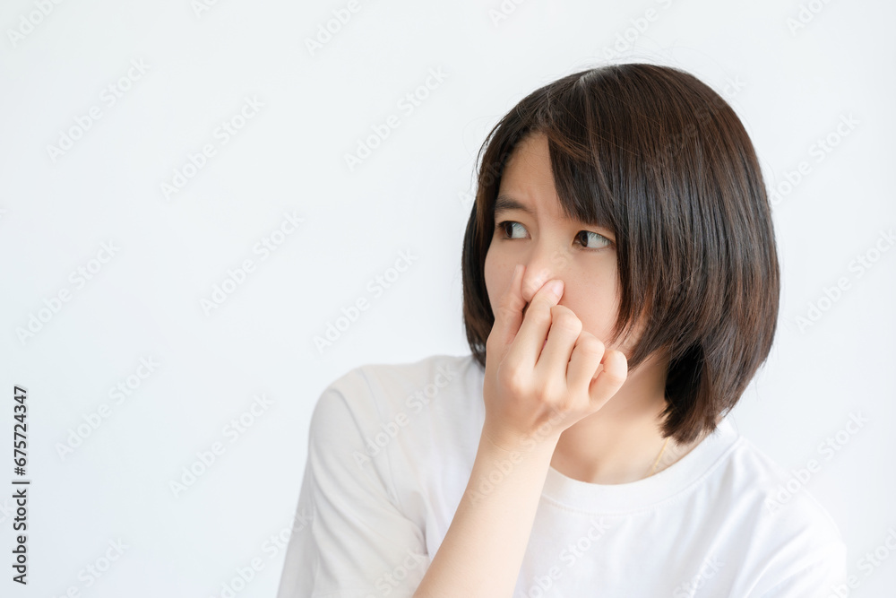 Asian woman with short hair covers her nose with her hand because something smells bad. Asian woman with short hair covers her nose with her hand because something smells bad.