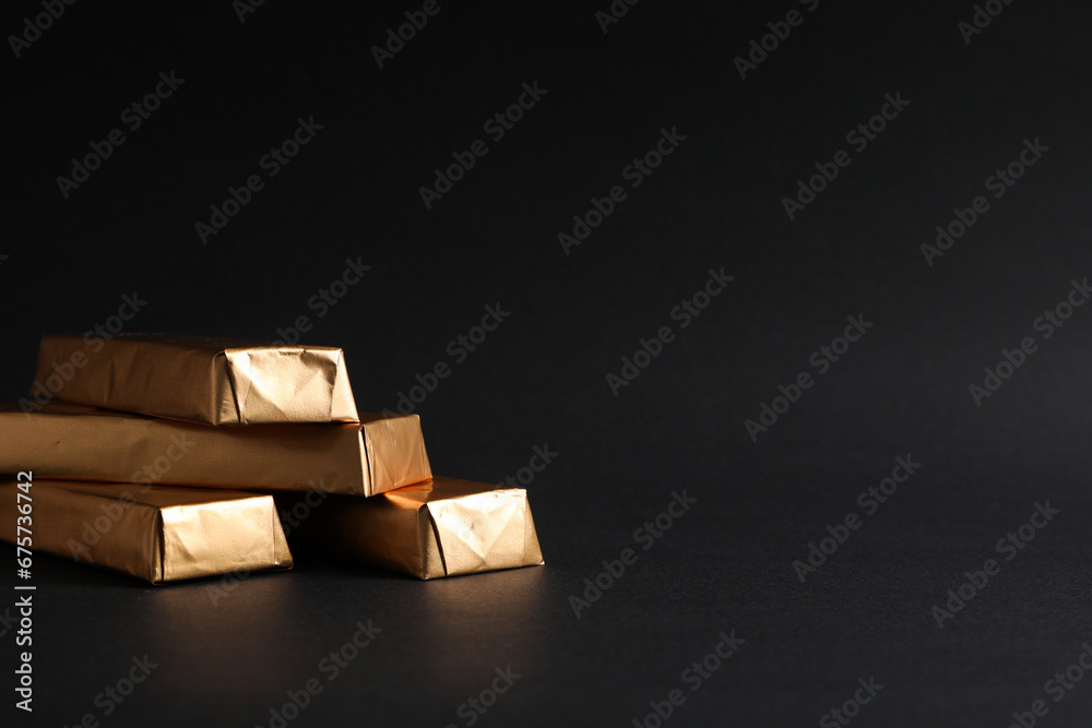 Chocolates in golden foil on black background, space for text
