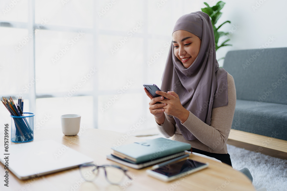 Obraz premium Muslim undergraduate student using mobile phone to contact friends.
