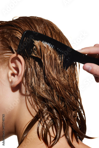 Foto Cropped image of girl with wet hair, brushing hair, applying nutrition mask against white studio background