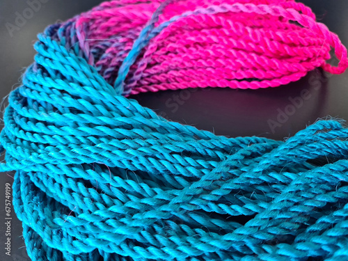 Colored braids with bright pink and blue elastic bands on a black background