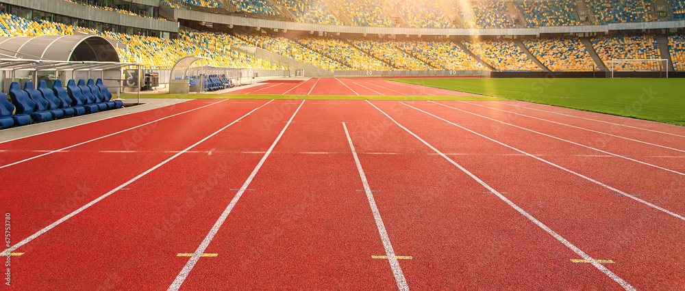 Red running track in a sports stadium in the sunlight. Sports boarder.