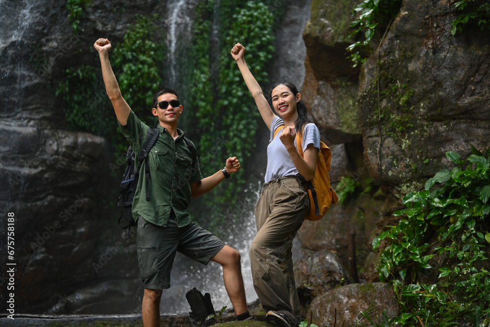 Obraz premium Young couple tourist raising hand to celebrating achievement, success and goal in forest