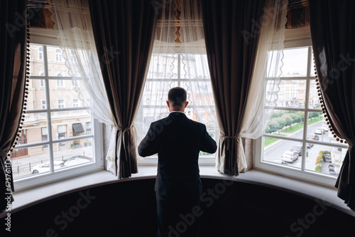 Rear view of a man looking out the window in a hotel room photo
