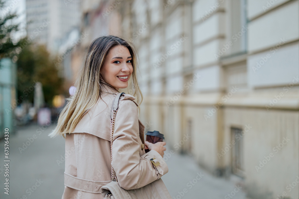 Woman walking while looking over her shoulder and drinking coffee takeaway Woman walking while looking over her shoulder and drinking coffee takeaway