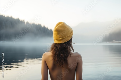 Young woman in a hat bathing in the cold water of the lake. Wim Hof method, cold therapy, breathing techniques, winter swimming, ice swimming.