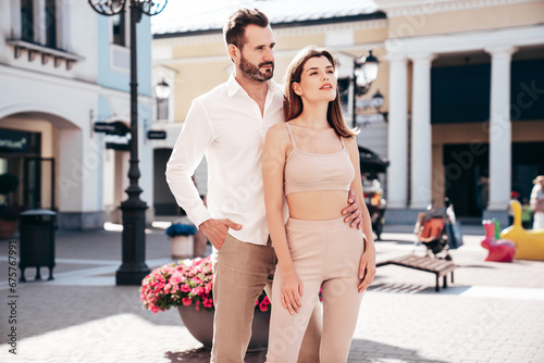 Beautiful fashion woman and her handsome elegant boyfriend in white shirt. Sexy brunette model in summer clothes. Fashionable confident couple posing in street Europe. Brutal man and female outdoors