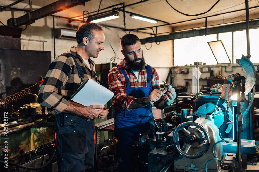 Two metallurgists measuring a roll cut metal piece in a metal factory.