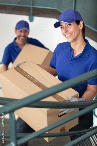 two young movers in blue uniform carrying cardboard boxes