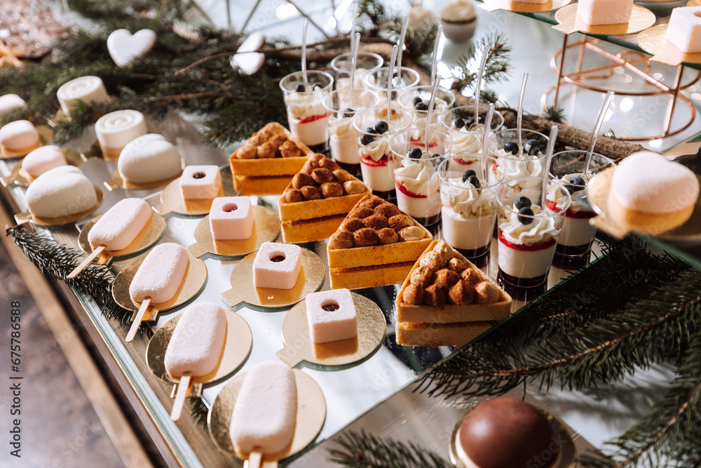A delicious wedding. White cake decorated with flowers. Candy bar for a banquet. Celebration concept. Fashionable desserts. Table with sweets, candies. Fruits