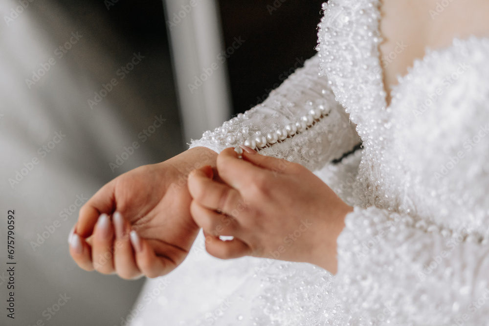 The bride fastens the sleeve of her wedding dress. Morning of the bride. Preparation. Wedding photography The bride fastens the sleeve of her wedding dress. Morning of the bride. Preparation. Wedding photography