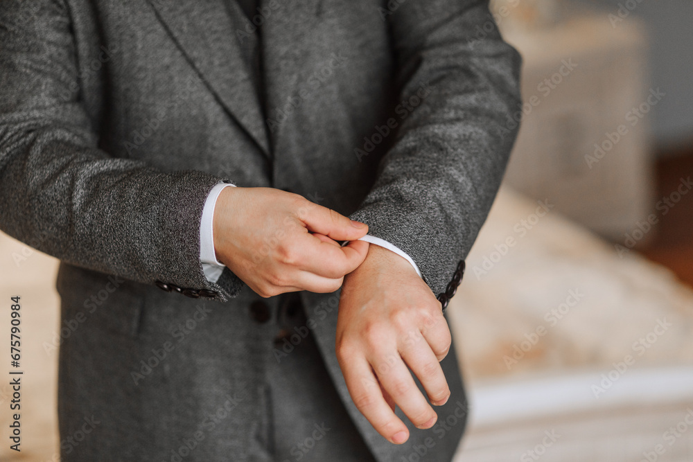 Obraz premium A man poses and adjusts a gray jacket. Portrait of the groom. Fashion and style. Business