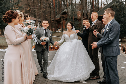 Bride and groom hugging, posing with friends. Friends are having fun. Happy moments. Wedding portrait in nature, wedding photo in light colors.