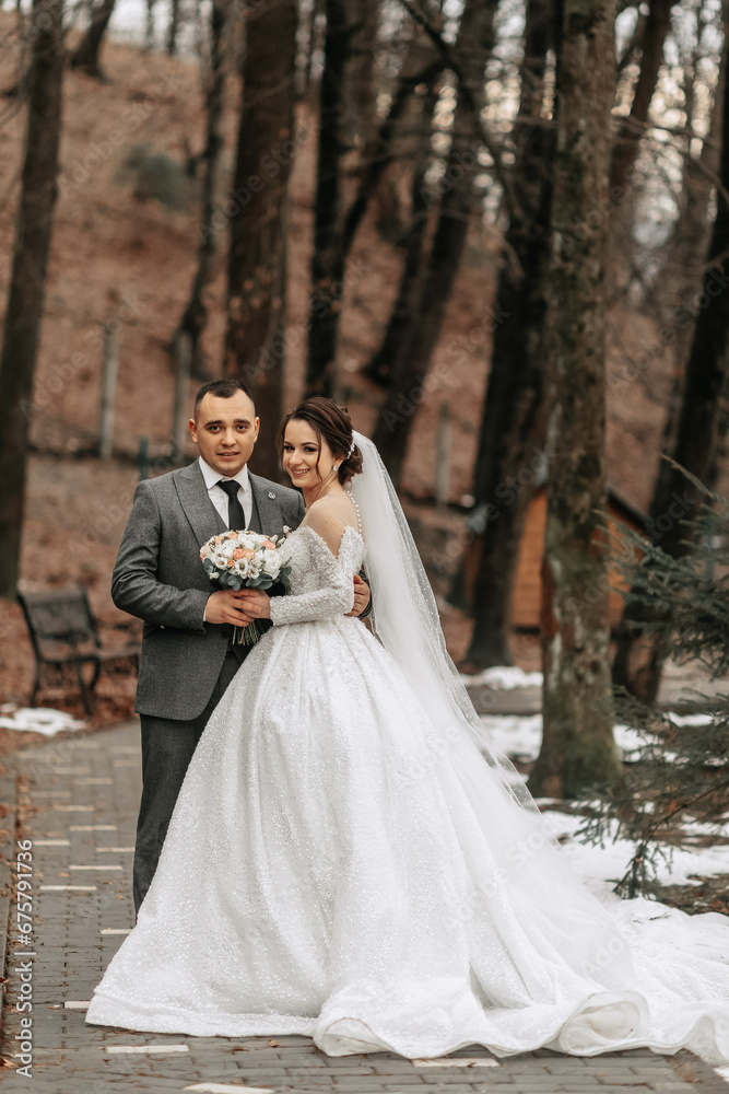 Portrait. The bride and groom are standing, holding a bouquet, posing in the forest. A walk in the forest. Winter wedding