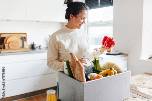 Smiling woman unpacking a box of fresh groceries